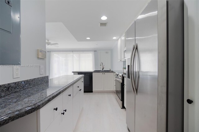 kitchen featuring white cabinetry, stainless steel appliances, dark stone countertops, sink, and ceiling fan