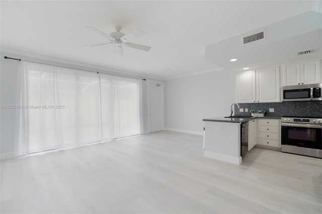 kitchen featuring white cabinets, appliances with stainless steel finishes, light hardwood / wood-style floors, decorative backsplash, and sink