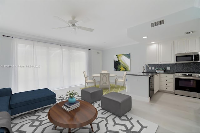 living room featuring ceiling fan, plenty of natural light, light hardwood / wood-style flooring, and sink