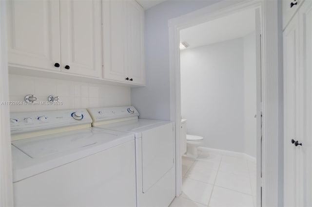 laundry room with light tile patterned flooring, cabinets, and washer and dryer