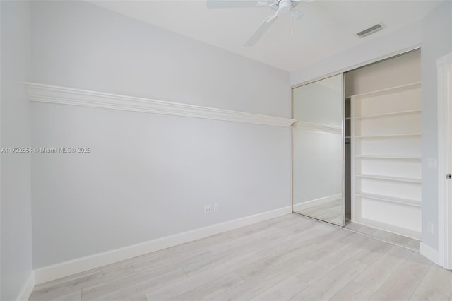 unfurnished bedroom featuring ceiling fan, a closet, and light wood-type flooring