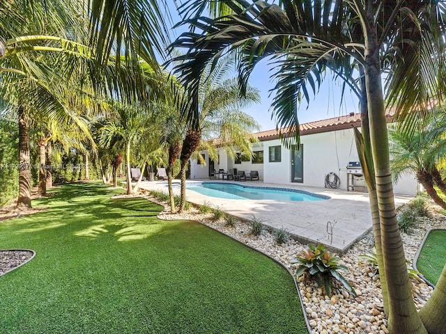 view of pool with a lawn and a patio