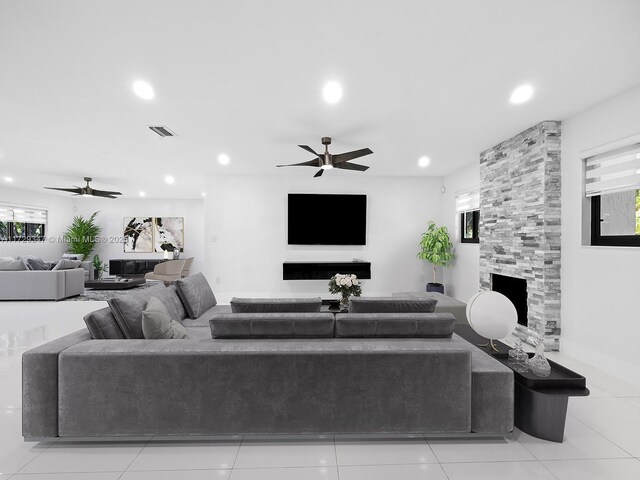 tiled living room with ceiling fan and a large fireplace