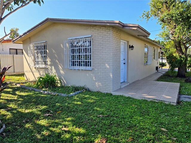 view of side of property with a patio area and a lawn