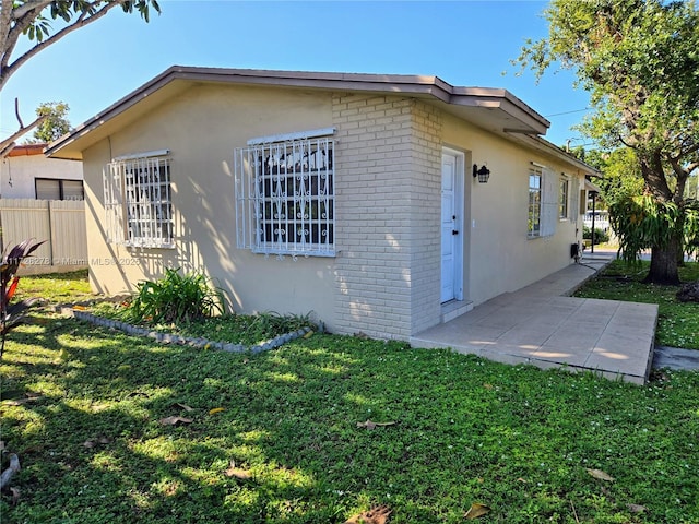 view of side of property with a patio area and a lawn