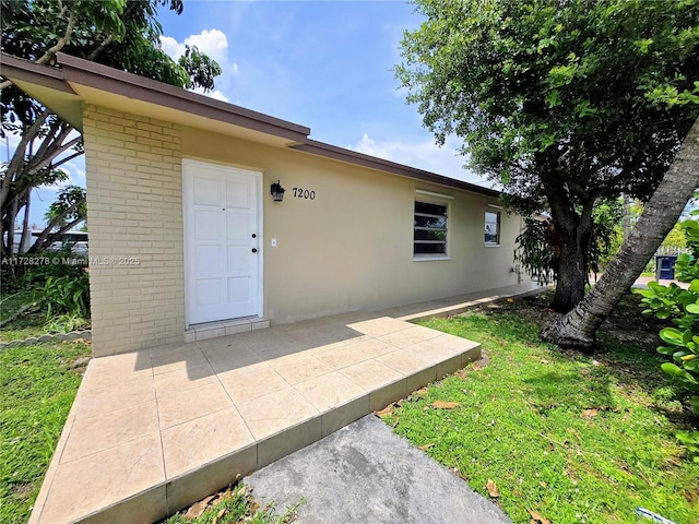 7200 NW 4th St, Miami, FL 33126 - entrance to property featuring brick siding, stucco siding, and a patio area