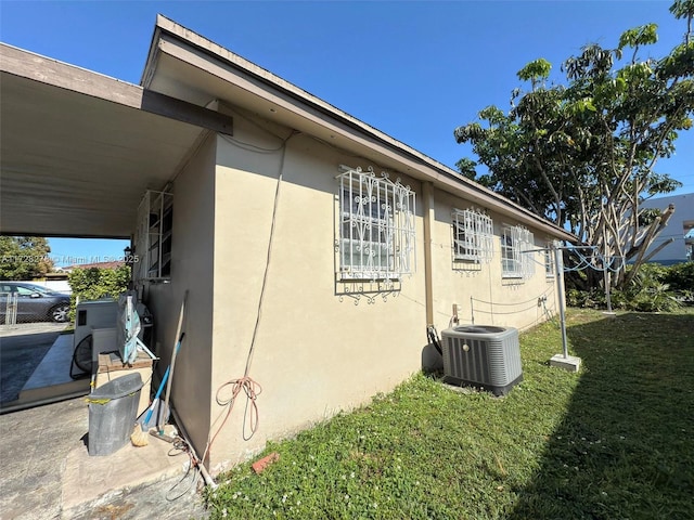 view of property exterior with central air condition unit and a lawn