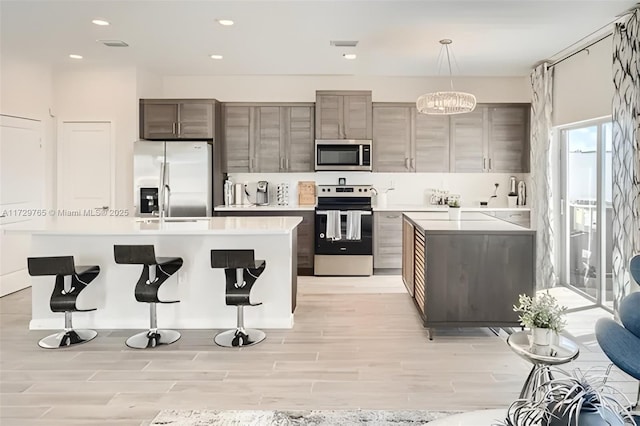 kitchen featuring light wood-type flooring, a center island, hanging light fixtures, and appliances with stainless steel finishes