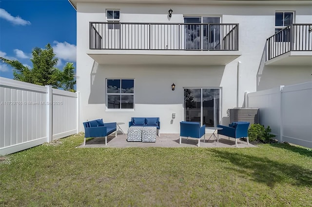 rear view of property featuring an outdoor living space, a patio, a lawn, and a balcony