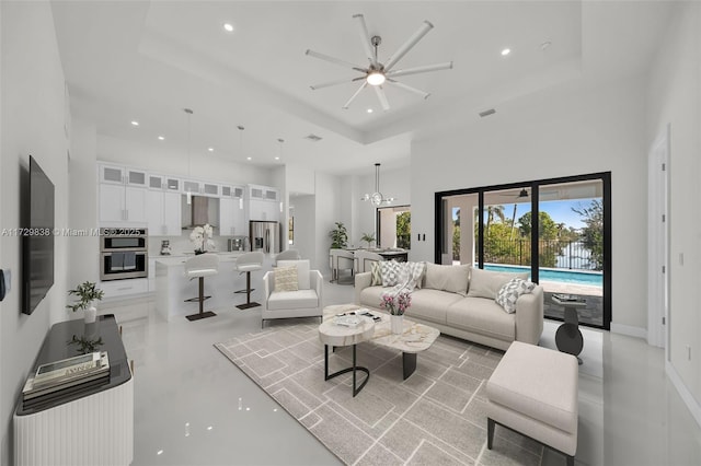 living room featuring a chandelier, a towering ceiling, and a tray ceiling