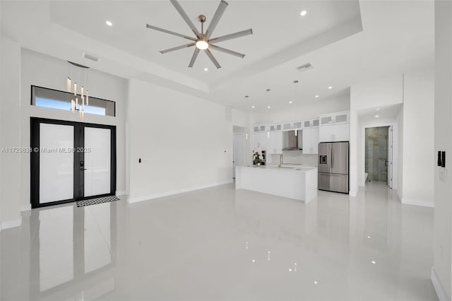 unfurnished living room featuring sink, a tray ceiling, and french doors