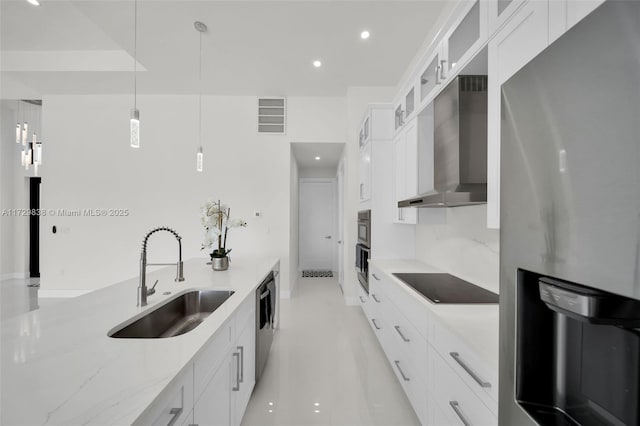 kitchen featuring white cabinetry, sink, decorative light fixtures, stainless steel appliances, and wall chimney exhaust hood