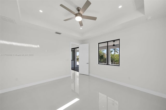 spare room with ceiling fan and a raised ceiling