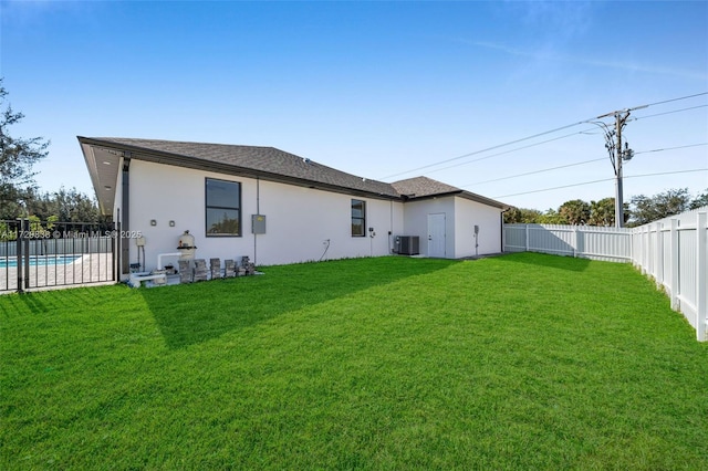 back of house with a fenced in pool, a yard, and cooling unit