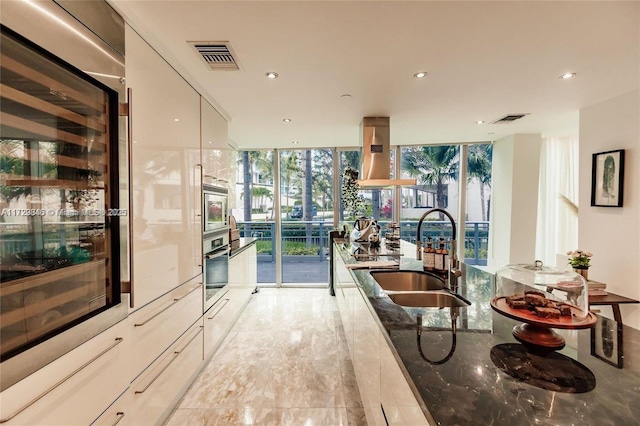 kitchen with sink, dark stone countertops, expansive windows, and appliances with stainless steel finishes