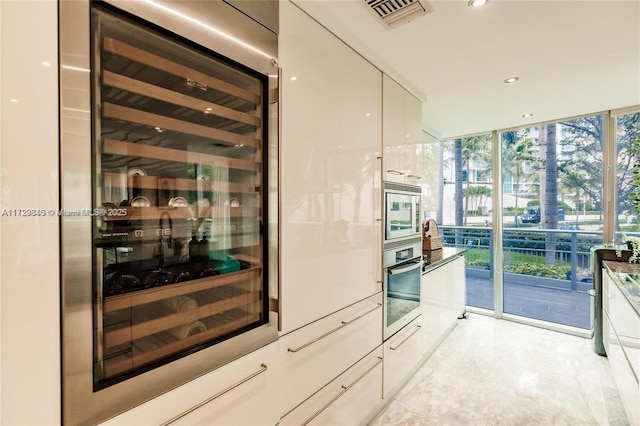 kitchen featuring white cabinets, a wall of windows, wine cooler, and stainless steel appliances