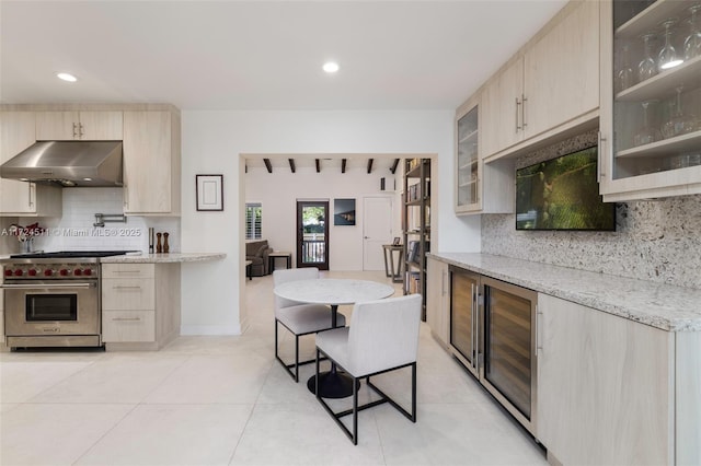 kitchen featuring light brown cabinets, wine cooler, light stone countertops, a breakfast bar area, and premium range