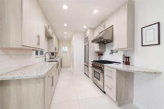 kitchen with light brown cabinets, high quality appliances, backsplash, light stone counters, and light tile patterned flooring