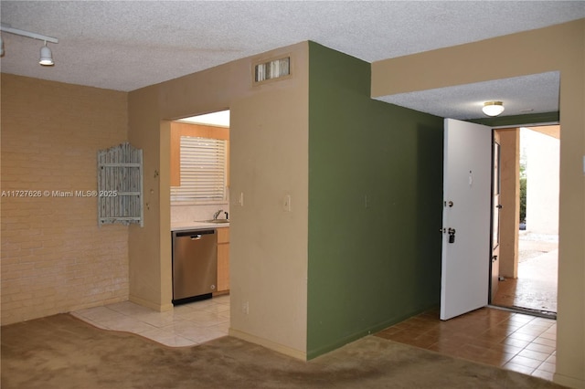 hallway with rail lighting, light tile patterned floors, and a textured ceiling