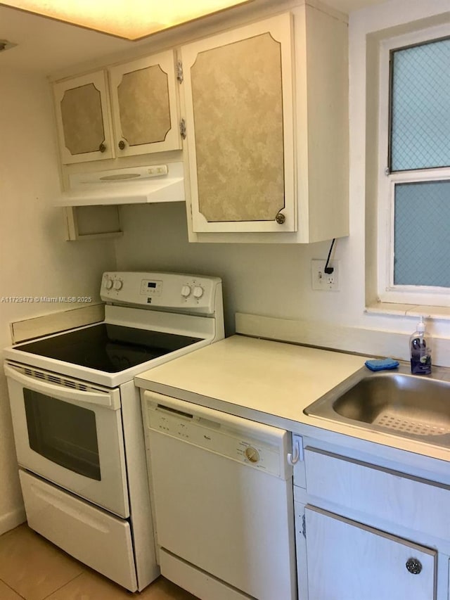 kitchen featuring white cabinets, white appliances, light tile patterned floors, and sink