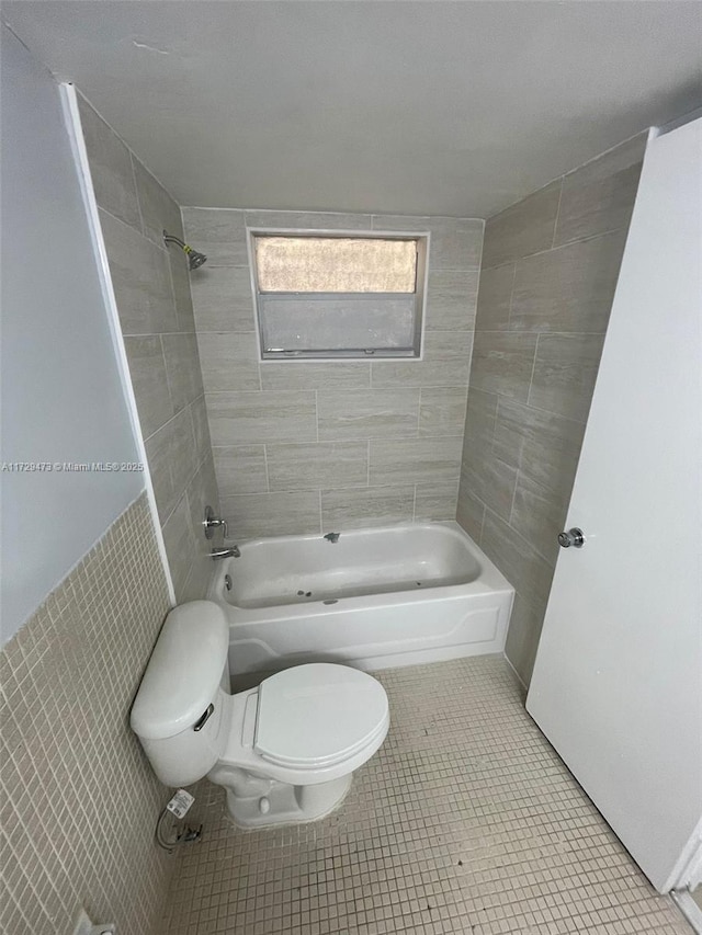 bathroom with tiled shower / bath combo, toilet, and tile patterned flooring