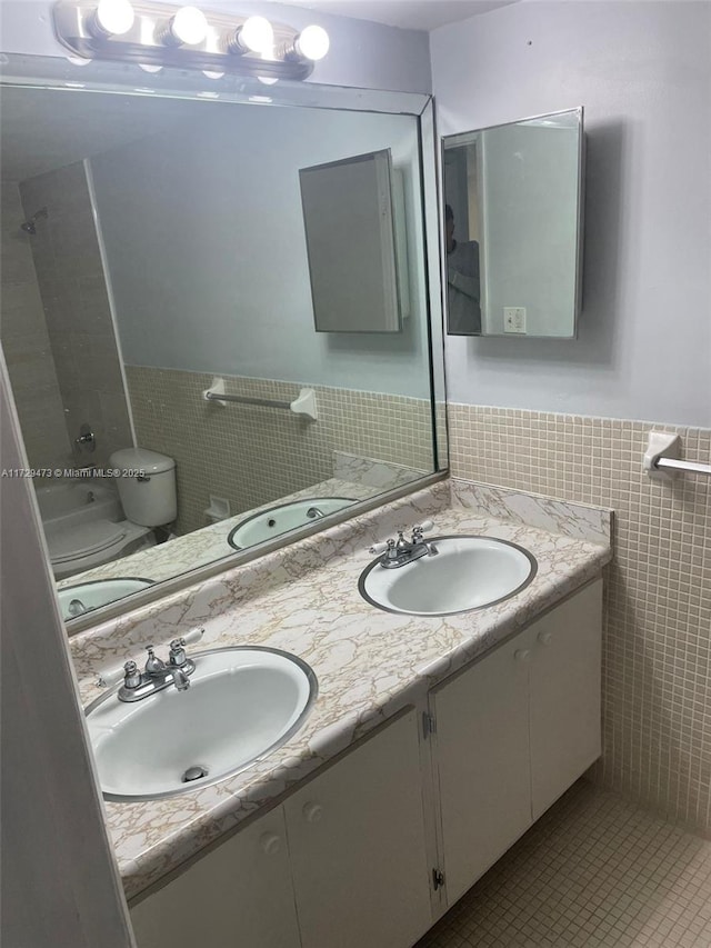 bathroom featuring tile walls, toilet, vanity, and tile patterned flooring