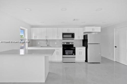 kitchen with sink, white cabinetry, stainless steel range with electric stovetop, and white fridge