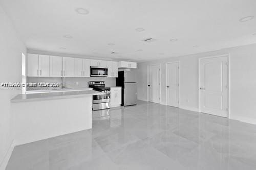 kitchen featuring stainless steel electric stove, white cabinets, white refrigerator, and kitchen peninsula