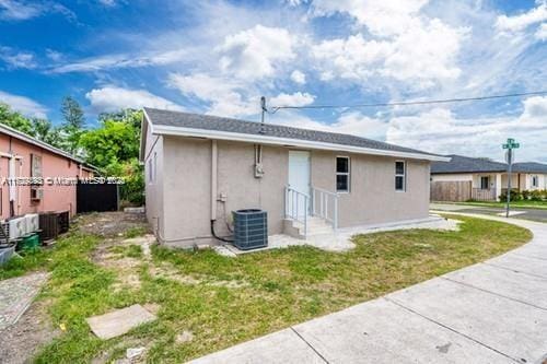 rear view of house with a lawn and central AC