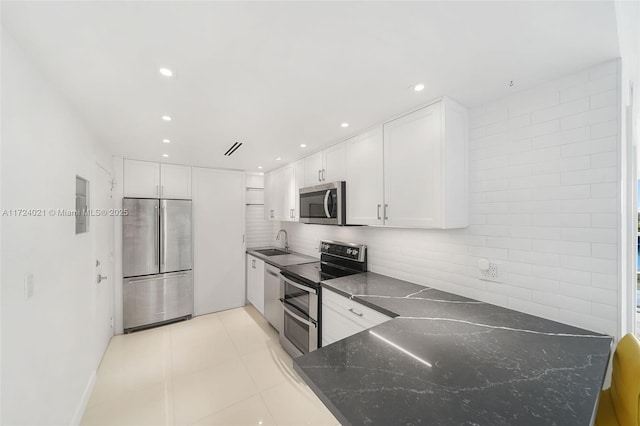 kitchen with tasteful backsplash, white cabinetry, light tile patterned floors, sink, and stainless steel appliances