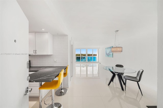 kitchen with decorative light fixtures, white cabinets, tasteful backsplash, and light tile patterned floors