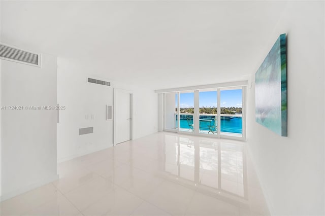 spare room featuring expansive windows and light tile patterned flooring