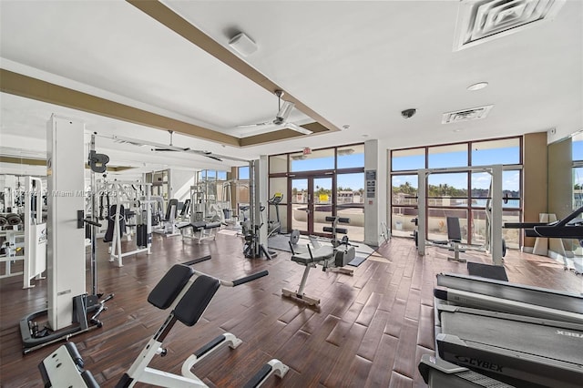 gym with a tray ceiling, ceiling fan, and wood-type flooring