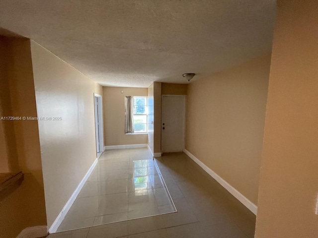 hallway featuring light tile patterned floors and a textured ceiling