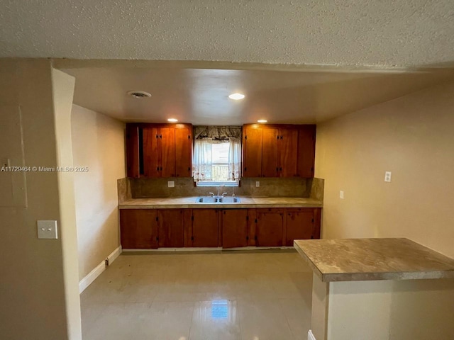 kitchen with sink, decorative backsplash, kitchen peninsula, and a textured ceiling