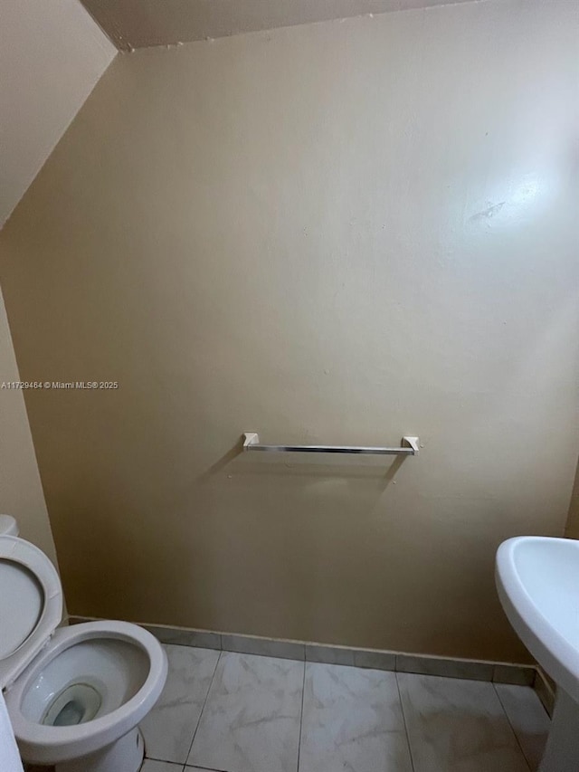 bathroom featuring vaulted ceiling, sink, and toilet