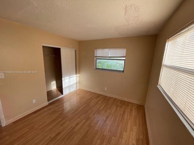 unfurnished bedroom with light hardwood / wood-style flooring, a closet, and a textured ceiling