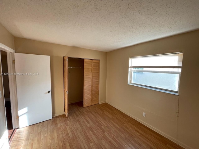 unfurnished bedroom with a textured ceiling, a closet, and light hardwood / wood-style flooring