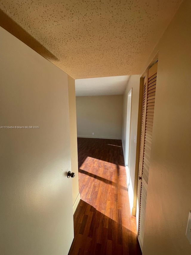 hall featuring dark hardwood / wood-style floors and a textured ceiling