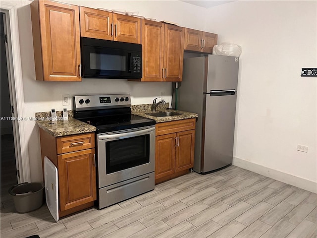 kitchen featuring sink, dark stone countertops, and appliances with stainless steel finishes