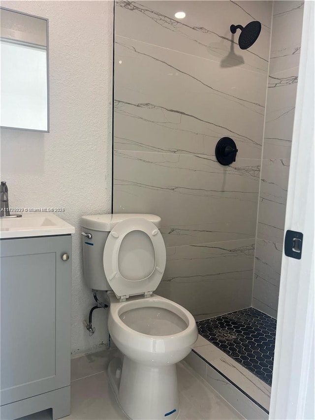 bathroom featuring tiled shower, toilet, and vanity