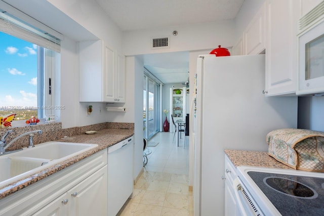 kitchen featuring sink, white appliances, light stone countertops, and white cabinets