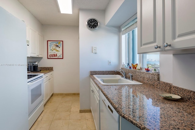 kitchen with light tile patterned flooring, white cabinetry, sink, dark stone countertops, and white appliances