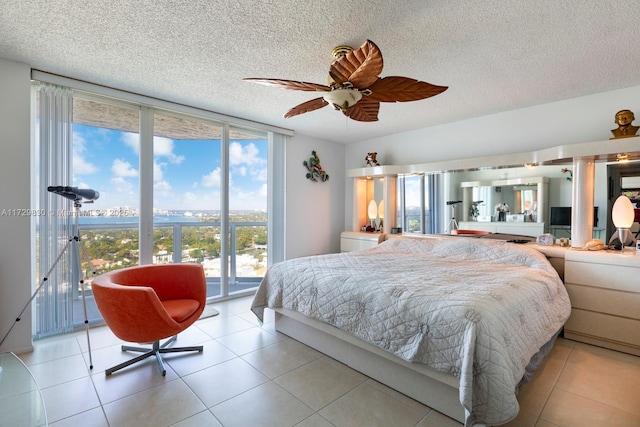 bedroom featuring light tile patterned flooring, expansive windows, access to outside, ceiling fan, and a textured ceiling