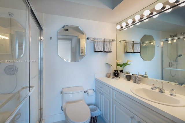 bathroom featuring vanity, a shower with shower door, and toilet