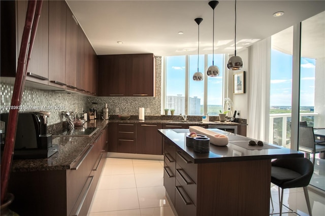 kitchen featuring sink, dark stone counters, a healthy amount of sunlight, and light tile patterned flooring