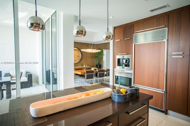 kitchen featuring light tile patterned flooring, paneled built in refrigerator, pendant lighting, and double oven