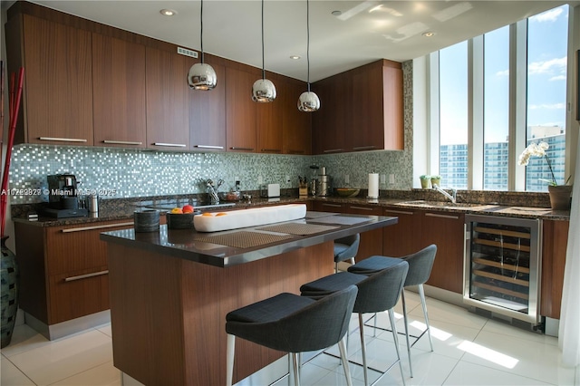 kitchen featuring sink, pendant lighting, beverage cooler, and a breakfast bar area