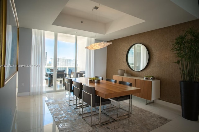 tiled dining area featuring a wall of windows and a raised ceiling