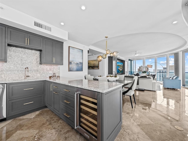 kitchen with decorative backsplash, wine cooler, light stone counters, and kitchen peninsula